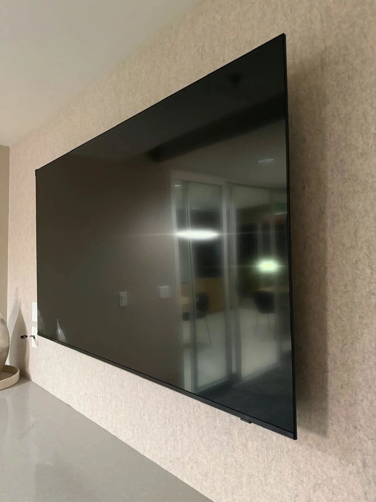 Large TV mounted flat against a textured wall above a counter